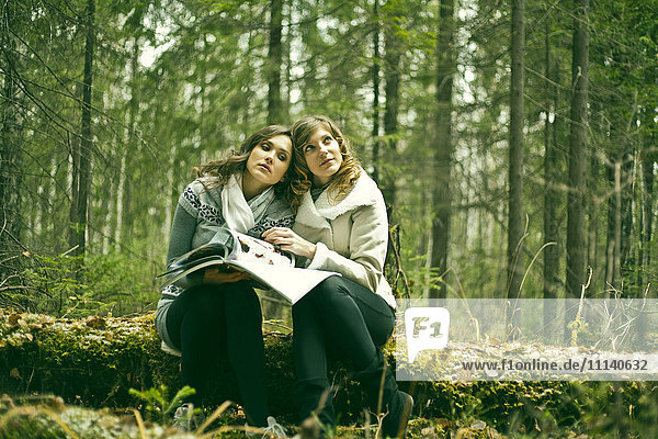 Kaukasische Frauen lesen eine Zeitschrift im Wald