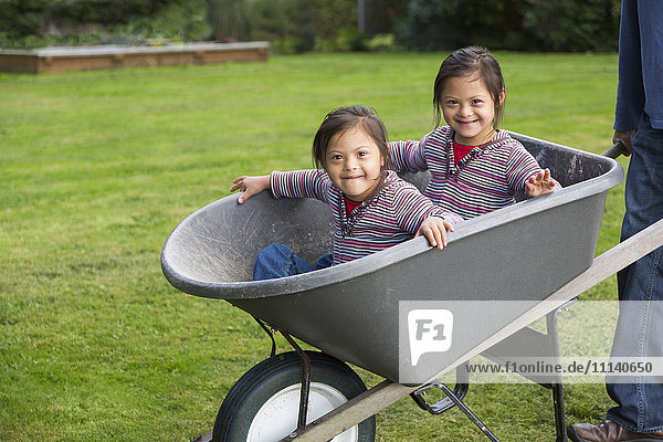 Twins with Down's Syndrome smiling in wheelbarrow