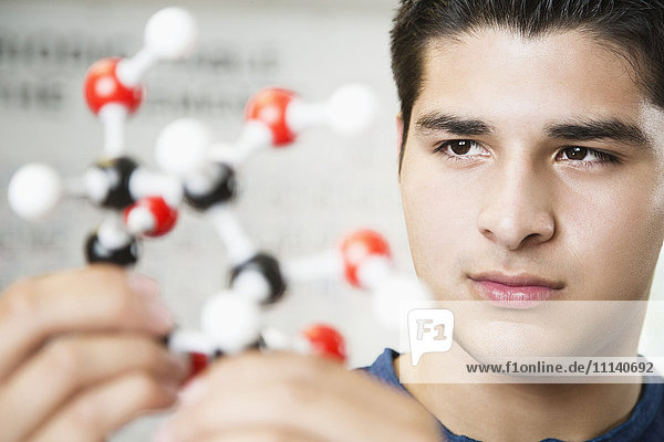 Hispanic student looking at chemistry model