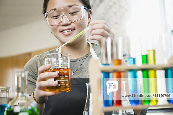 Asiatischer Schüler bei der Arbeit mit Chemikalien im Klassenzimmer
