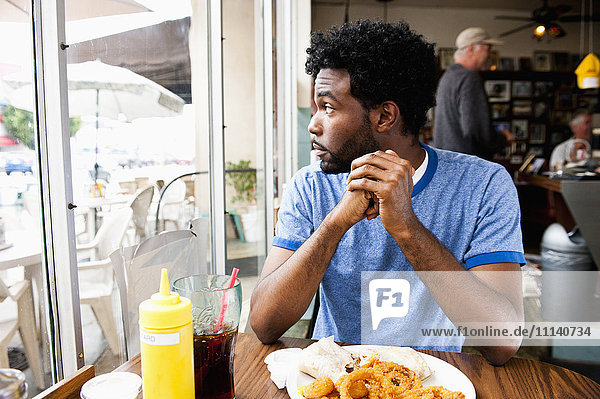 Afroamerikanischer Mann schaut aus dem Fenster eines Diners
