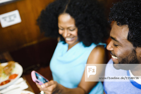 Smiling couple looking at cell phone in diner