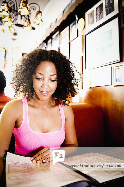 Lächelnde afroamerikanische Frau liest Speisekarte in einem Diner