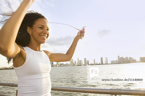 Lächelnde hispanische Frau beim Abseilen am Wasser