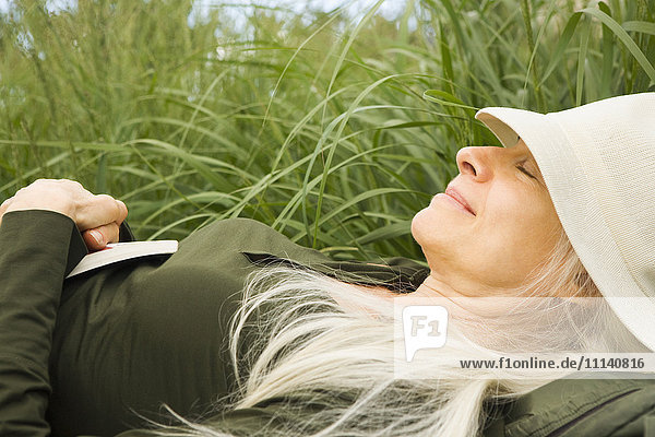 Lächelnde kaukasische Frau  die im Gras schläft