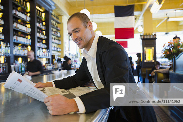 Kaukasischer Mann liest Zeitung in einem Cafe