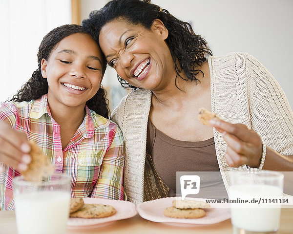 Mutter und Tochter essen gemeinsam Kekse und Milch
