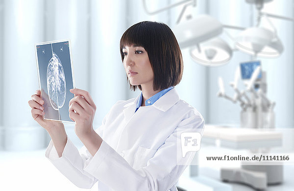 Gemischtrassiger Arzt schaut im Operationssaal auf eine digitale Tafel