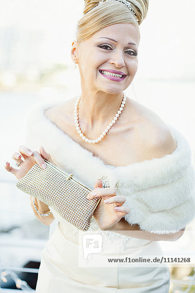 Lächelnde hispanische Braut mit Handtasche