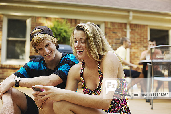 Couple hanging out together on patio looking at cell phone