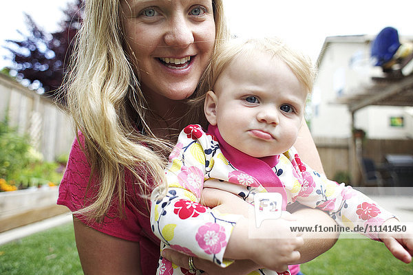 Kaukasische Mutter hält Tochter im Hinterhof