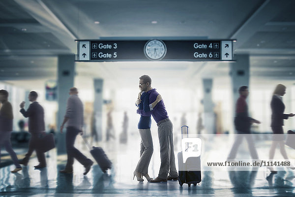 Kaukasisches Paar  das sich im Flughafen umarmt