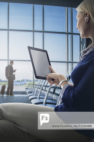 Kaukasische Frau benutzt digitales Tablet im Flughafen