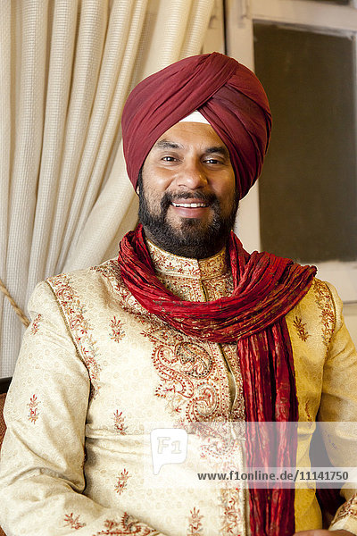 Lächelnder gemischtrassiger Mann in traditioneller indischer Kleidung