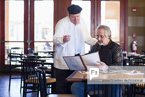 Caucasian man talking to chef in restaurant