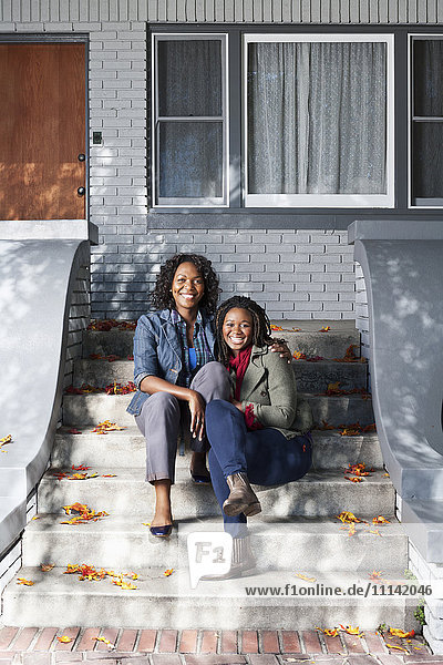 Schwarze Mutter und Tochter sitzen auf der Treppe