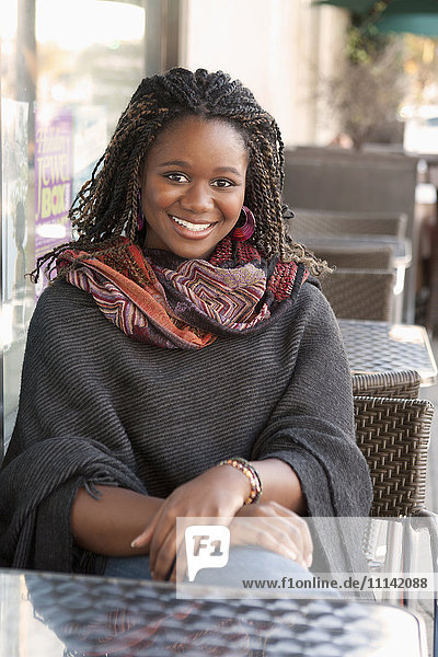 Schwarze Frau sitzt in einem Straßencafé