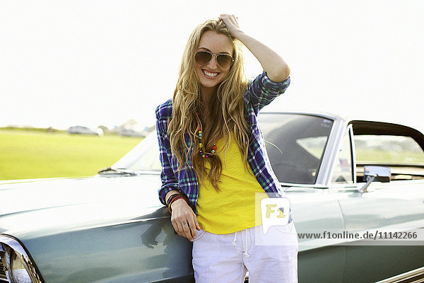 Smiling Caucasian woman leaning against car