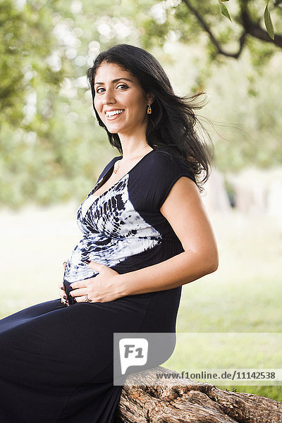 Mixed race pregnant woman sitting outdoors