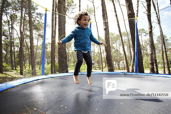 Gemischtrassiges Mädchen springt auf Trampolin