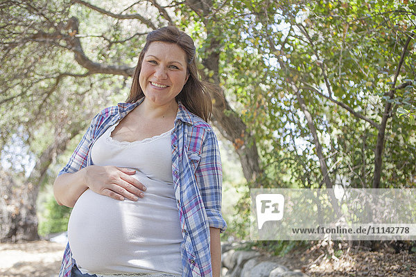 Pregnant Caucasian woman standing in park