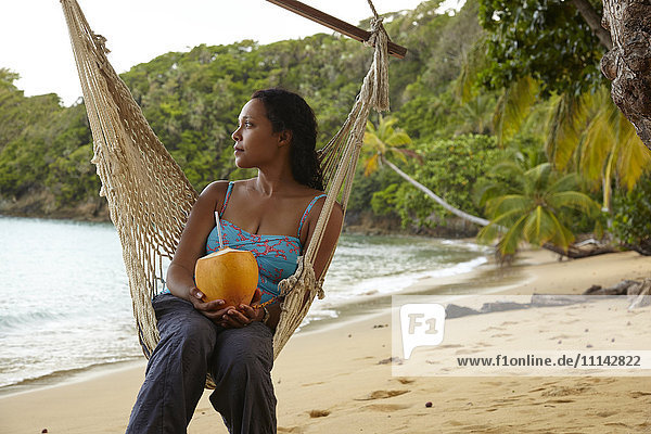 Gemischtrassige Frau entspannt sich in Hängematte am Strand