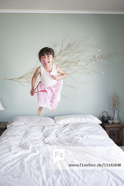 Hispanisches Mädchen springt auf Bett