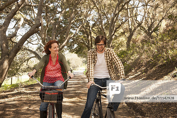 Couple riding bicycles on rural road