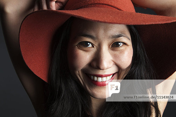 Lächelnde asiatische Frau mit rotem Hut