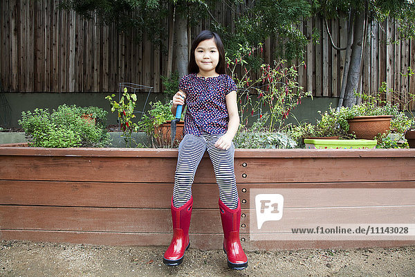 Mixed race girl wearing rain boots in backyard
