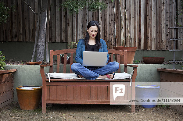 Koreanische Frau benutzt Laptop im Hinterhof