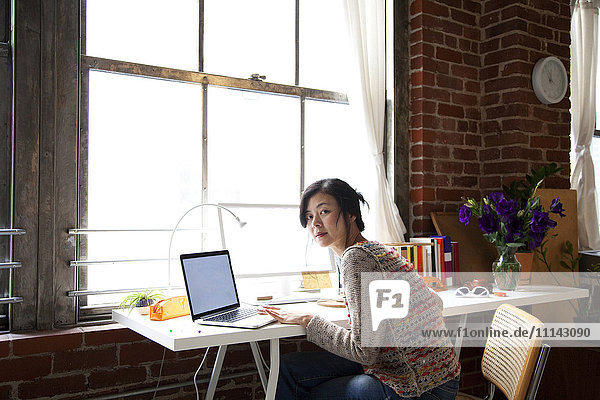 Taiwanesische Frau benutzt Laptop im Heimbüro