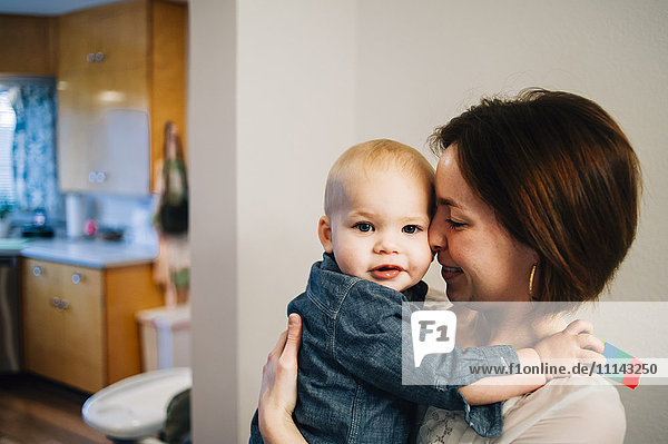 Smiling mother nuzzling son in kitchen