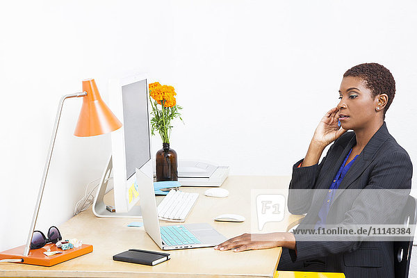 Black businesswoman talking on cell phone at office desk