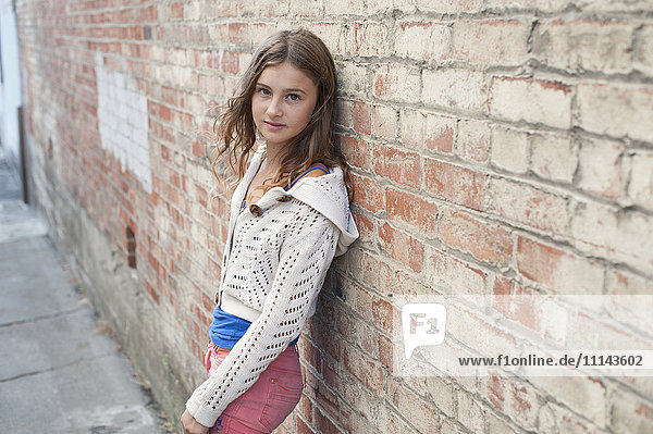 Smiling girl leaning on brick wall