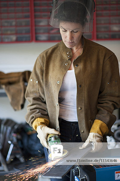 Artisan grinding metal in garage workshop