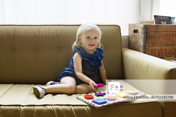 Girl playing with wooden blocks on sofa