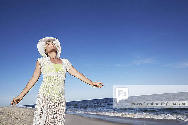 Ältere Frau am tropischen Strand stehend