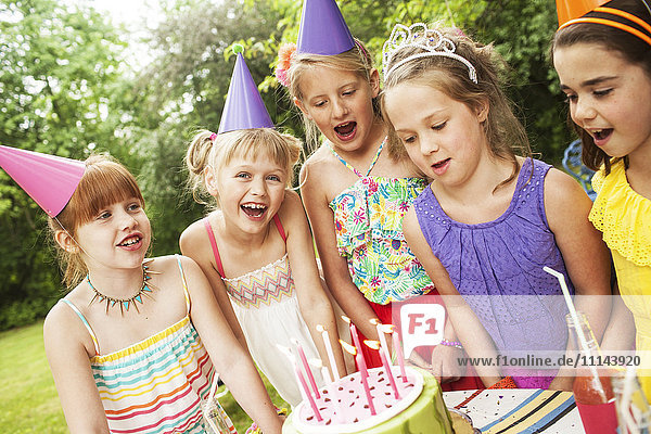 Mädchen bewundern Kuchen bei Geburtstagsfeier im Freien