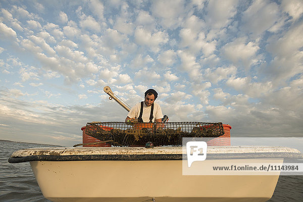 Kaukasischer Fischer untersucht das Netz auf dem Boot