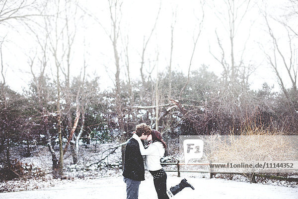 Couple kissing in snowy rural field
