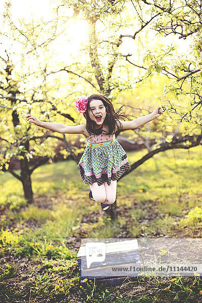 Mädchen springt vor Freude im Obstgarten