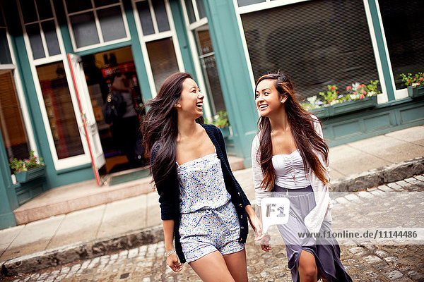 Lachende Frauen beim Überqueren einer Kopfsteinpflasterstraße