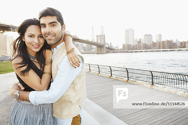 Indian couple hugging by New York city skyline  New York  New York  United States