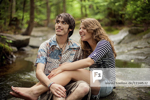 Couple sitting barefoot on boulders in forest