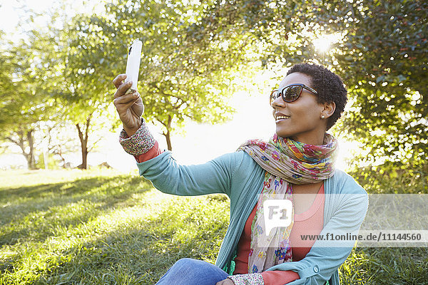 Schwarze Frau benutzt Mobiltelefon im Park