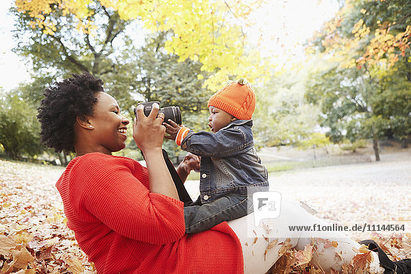 Schwarze Mutter fotografiert ihren kleinen Sohn im Park