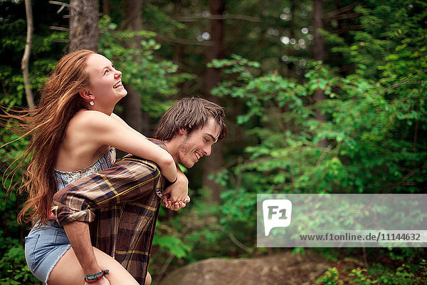 Man carrying girlfriend piggyback in forest
