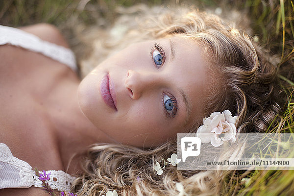 Close up of woman with blue eyes laying in grass