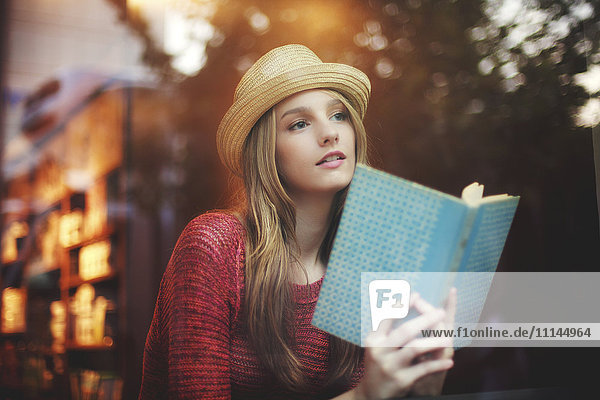 Mädchen liest Buch am Fenster